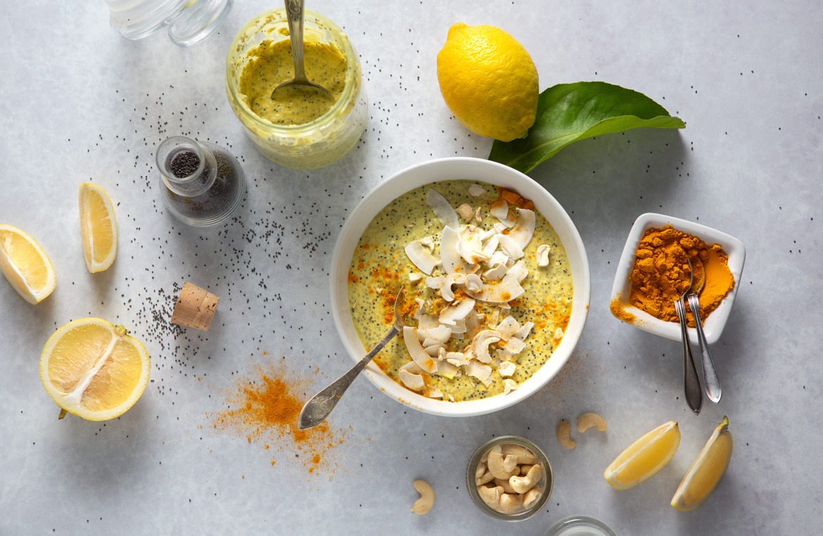 Bowl of yellow chia pudding styled with fresh Italian lemons, nuts and spices. 